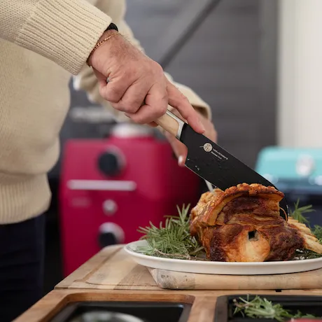 Mann schneidet Fleisch in der Küche mit dem Santoku von Everdure.