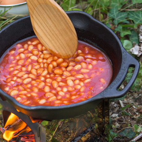 Gusseisenpfanne mit Bohnen in Tomatensauce, auf offenem Feuer gekocht