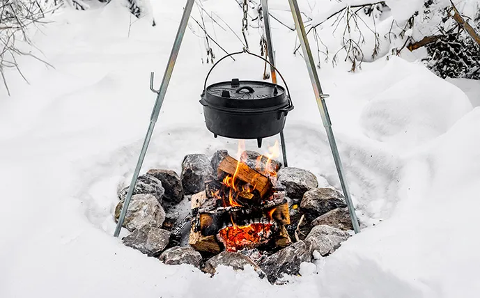 feuertopf-an-einem-dreibein-über-dem-feuer-umgeben-von-schnee