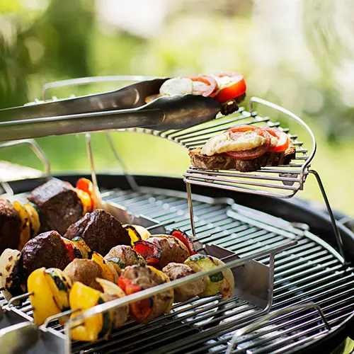 Grill mit Fleischspießen und Grillzange im Freien