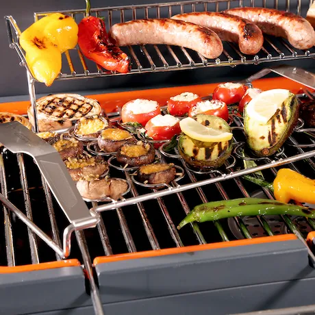 Grill mit gegrilltem Gemüse und Würstchen auf einem Edelstahlrost