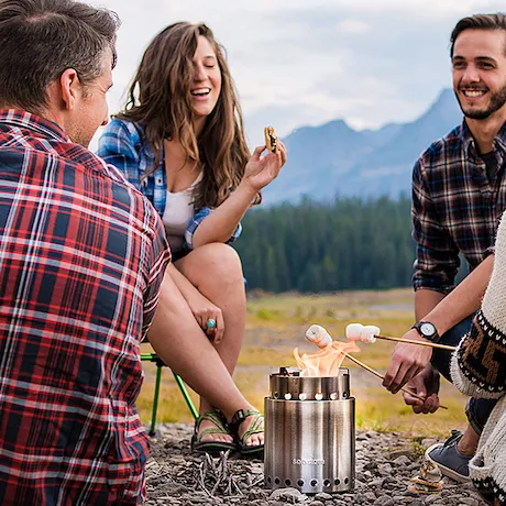 Eine Gruppe von vier Freunden, die am Lagerfeuer Marshmallows rösten und eine gute Zeit genießen.